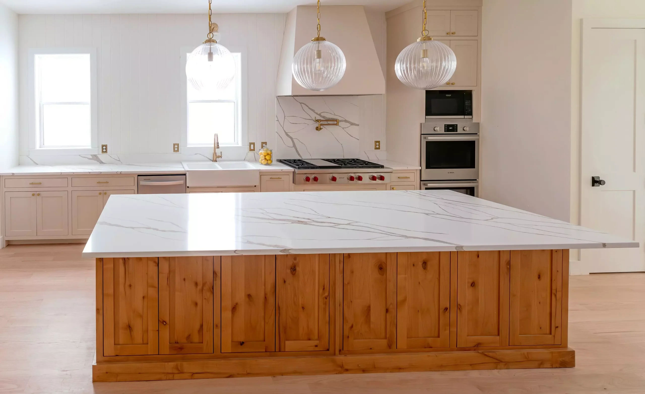 Luxurious kitchen island in Oak Cliff, Dallas, TX featuring a Calacatta River Gold quartz countertop with white and gold veining, and wooden cabinetry