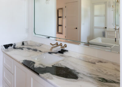 Elegant bathroom featuring a Bianca Lasa Macchia Vecchia 2cm Quartzite countertop on a white vanity with gold fixtures and a modern bathtub.