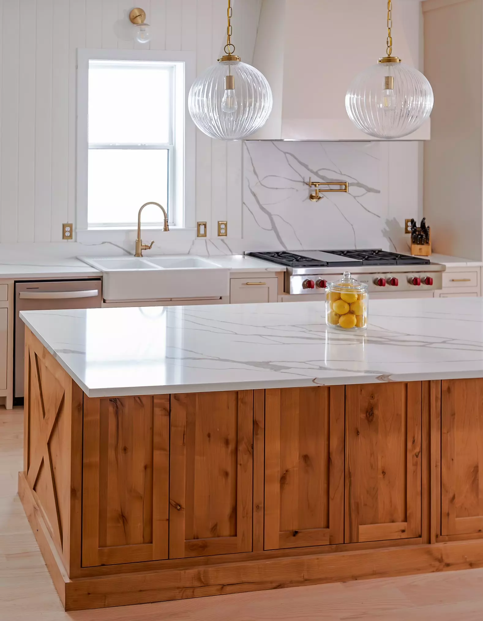 Luxurious kitchen island in Oak Cliff, Dallas, TX featuring a Calacatta River Gold quartz countertop with white and gold veining, and wooden cabinetry