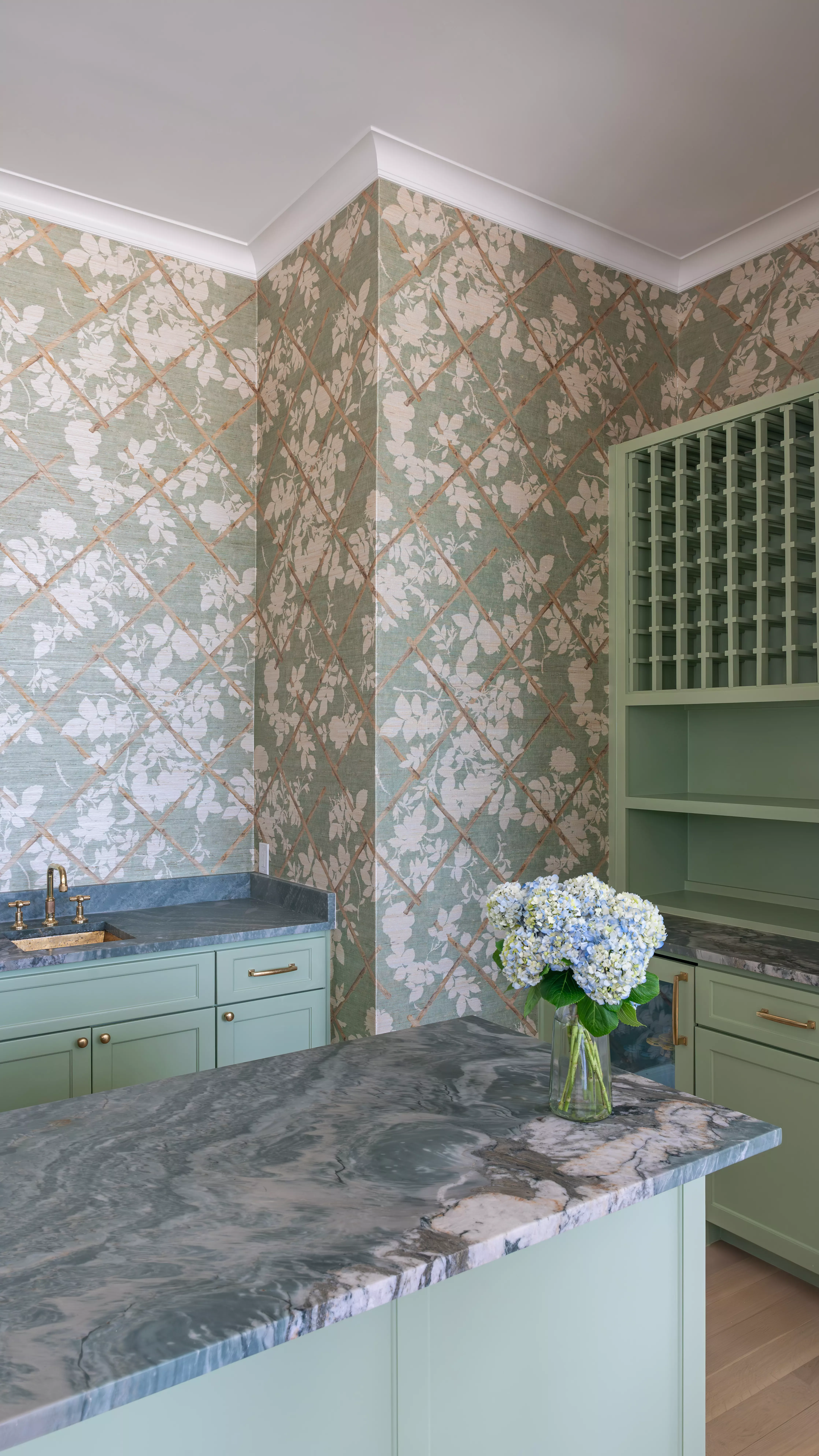 Text: Home bar featuring a Rio Fantastico Quartz countertop with elegant floral wallpaper and mint cabinetry