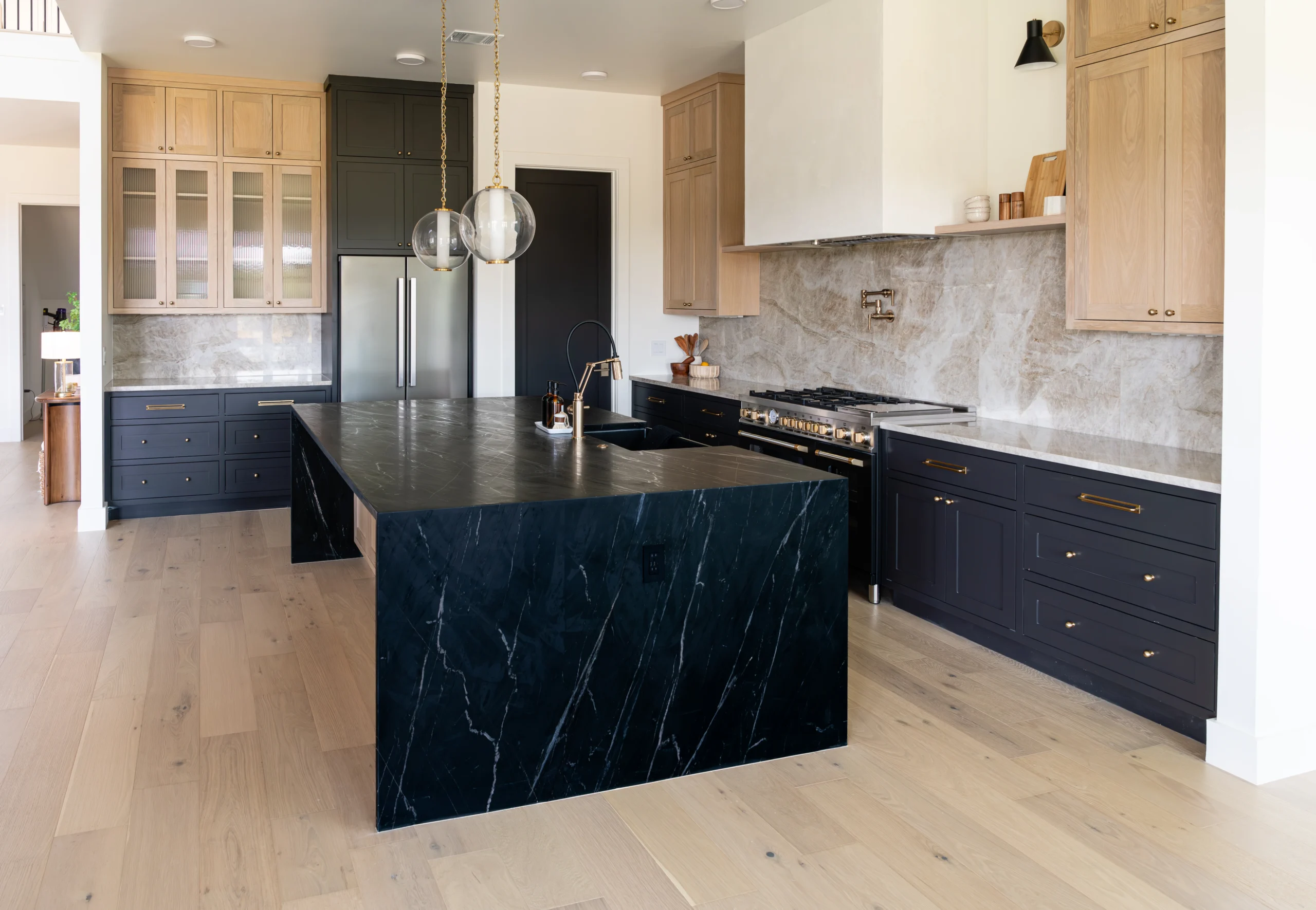 Modern kitchen featuring a black marble island, wooden cabinets, and stainless steel appliances